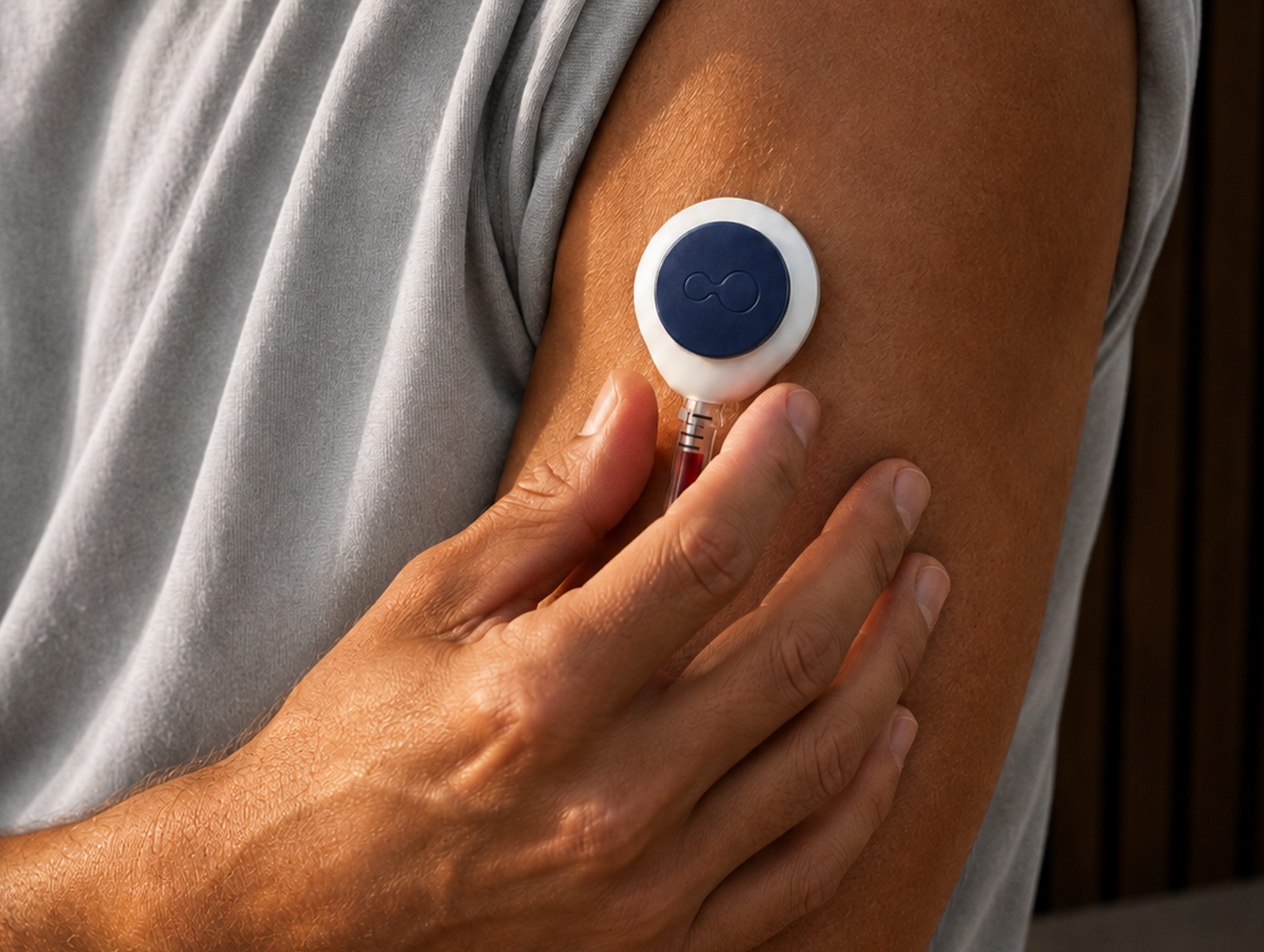 Close-up of a hand holding a small self-collection blood sampling device against a bare upper arm